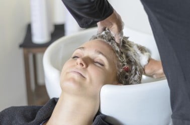 Vrouw ontspant bij de kapper tijdens wasbeurt