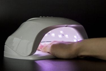 Hand in uv-lamp voor het uitharden van gelnagels. Dit kan soms een branderig gevoel veroorzaken