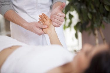 massagetherapeut geeft handreflexologie behandeling