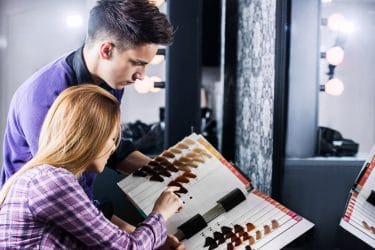 Kapper helpt vrouw bij het kiezen van een nieuwe haarkleur