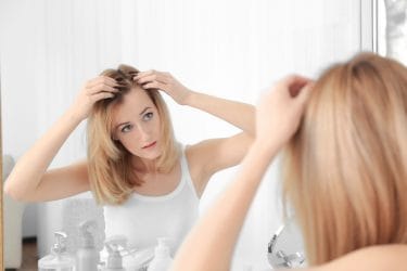 Vrouw bekijkt hoofdhuid vanwege mogelijk haaruitval, ze zou graag dikker haar hebben.