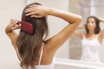 vrouw kamt haar met een paddle brush
