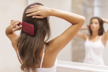 vrouw kamt haar met een paddle brush
