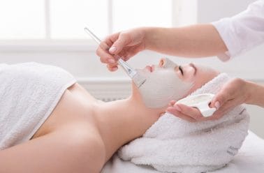 vrouw ontvangt een peeling met fruitzuren van een deskundige schoonheidsspecialiste