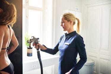 Vrouw ondergaat een professionele behandeling spray tanning in de winter