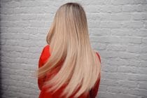 Blonde vrouw showt resultaat na een keratine haarbehandeling.