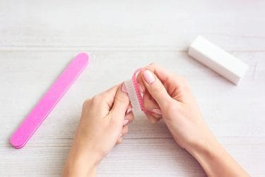 Vrouw verwijdert thuis gelnagels in coronatijden.