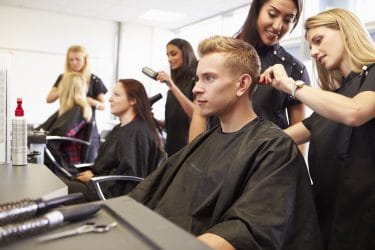 Studenten volgen een praktijkles tijdens hun opleiding kapper, een onmisbaar beroep.