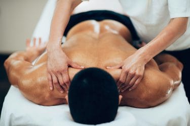 Man met overbelaste spieren ondergaat een sportmassage.