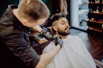 het trimmen en contouren van een strakke baard door een barbier.