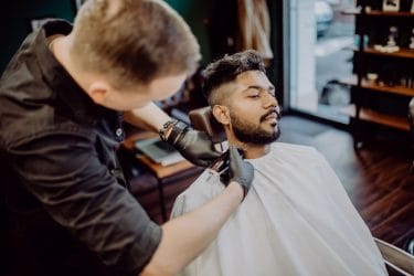 het trimmen en contouren van een strakke baard door een barbier.